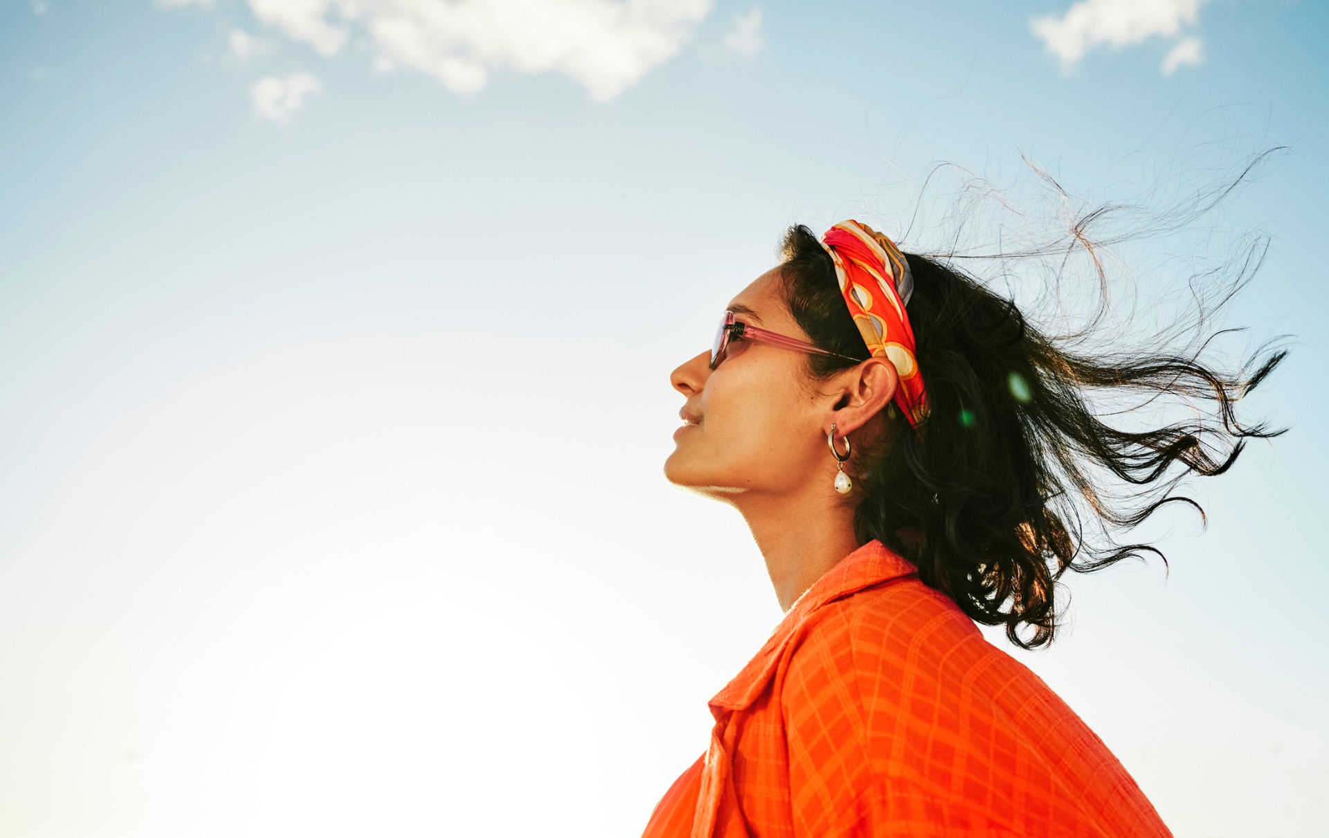 Vrouw met oranje blouse kijkt omhoog naar de lucht